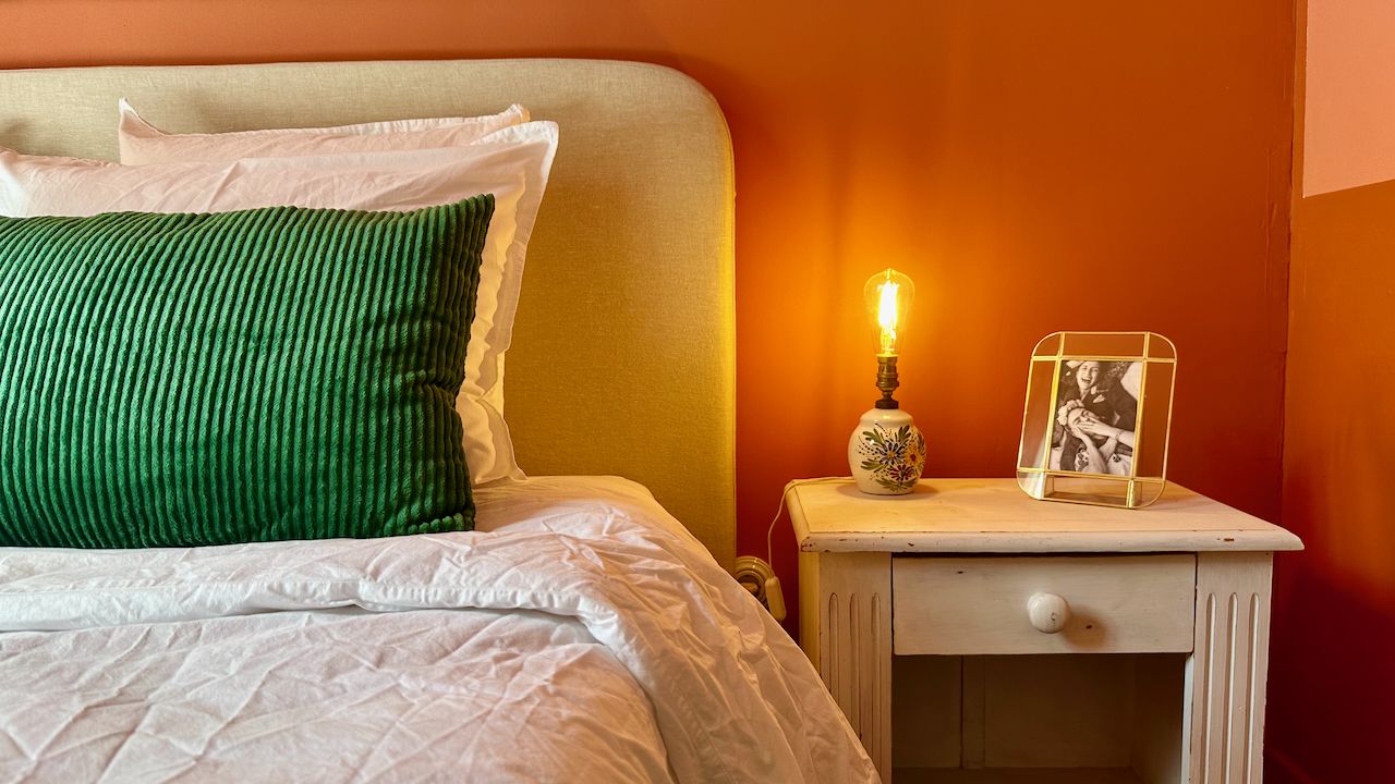 Chambre aux murs orange, coussin vert, bougie allumée